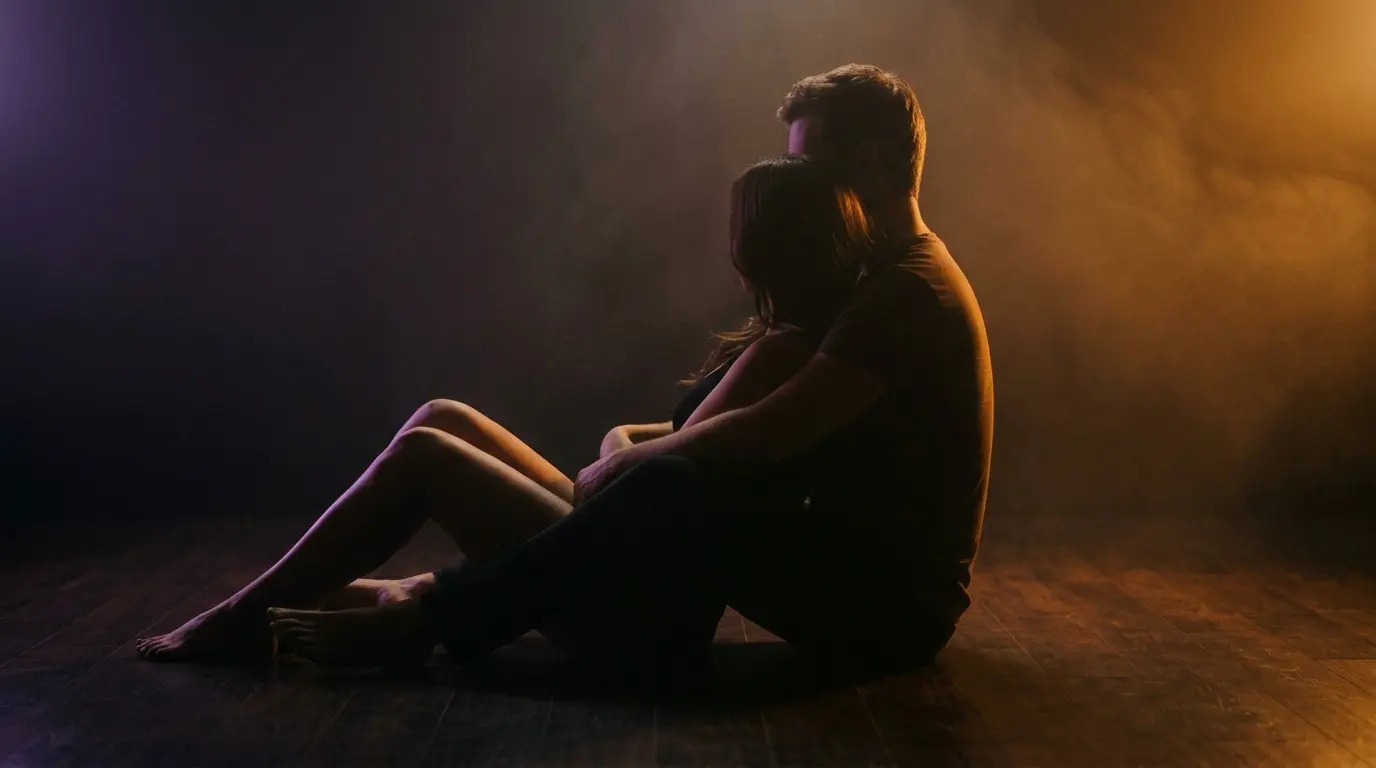 Abstract artistic silhouette of seated couple in floor position with warm amber side lighting and purple ambient accents