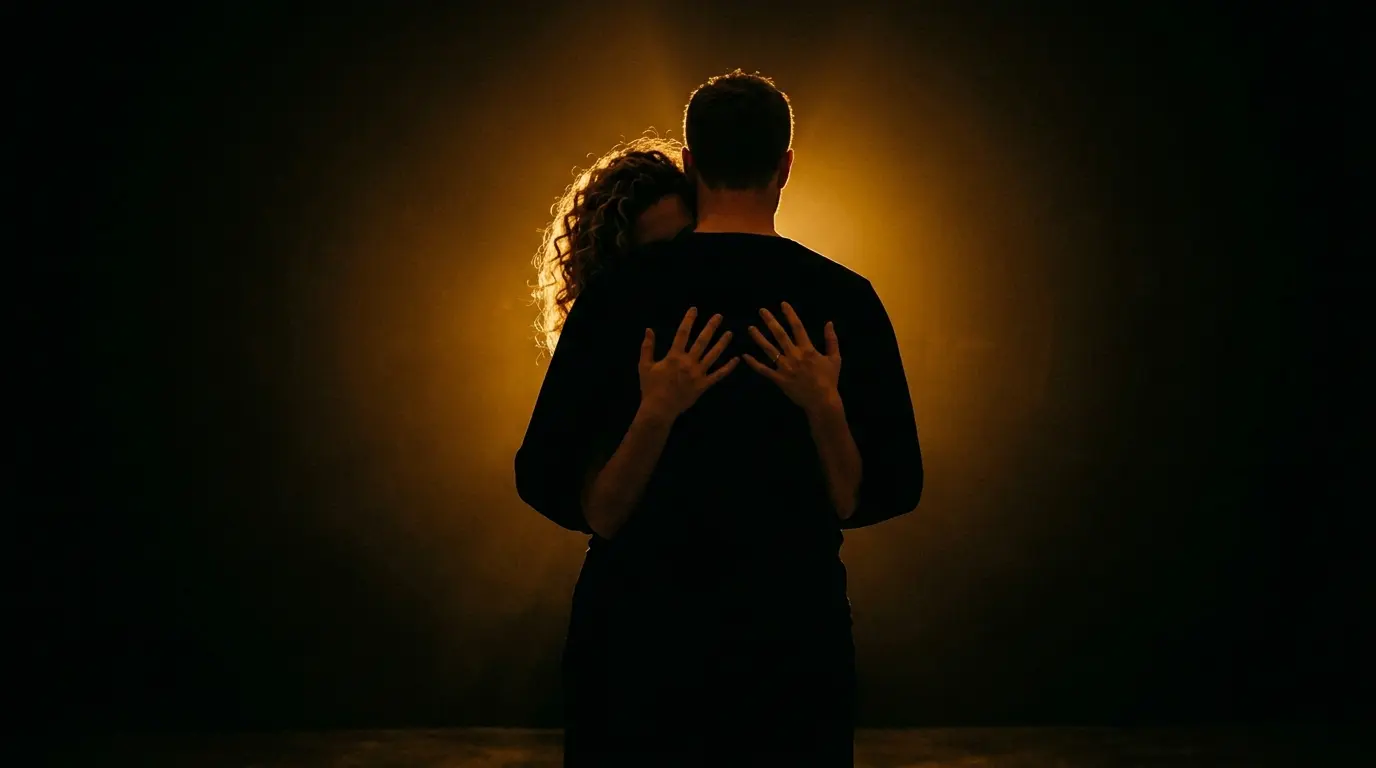 Artistic silhouette of couple in embrace position showing the reach around concept with golden backlight